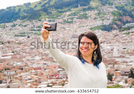 Young latin girl take a selfie from with his phone on summer, behind a urban city. Urban life concept