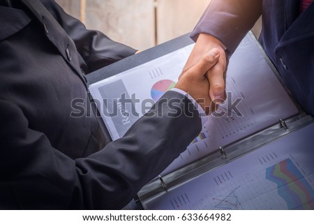 Two business man shaking hands during a meeting in the office, on documents.