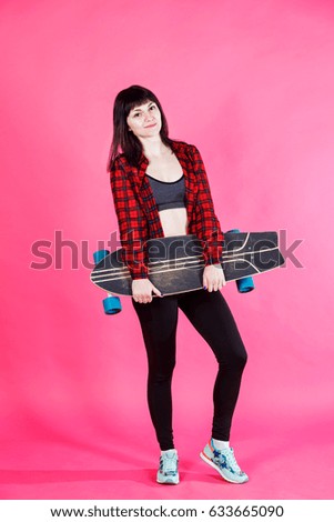 Attractive fitness young woman with the longboard in her hands on the pink background