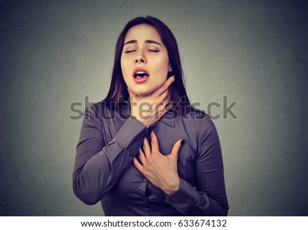 Young woman having asthma attack or choking can't breath suffering from respiration problems isolated on gray background   Royalty-Free Stock Photo #633674132