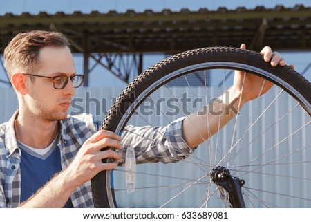 The mechanic man checks transmission system of the bicycle outdoor.