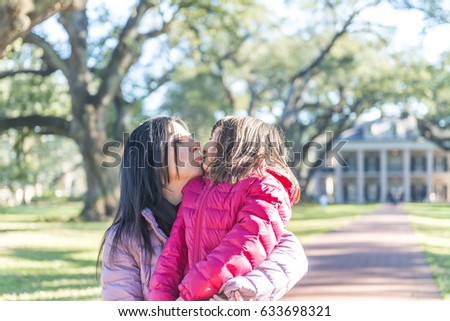 Mother and daughter kissing on a beautiful park