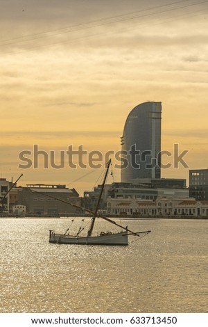 Sunrise at the port of Barcelona, at the end of the Ramblas. In the photo, a fishing boat and sailing hotel. Barcelona, Spain