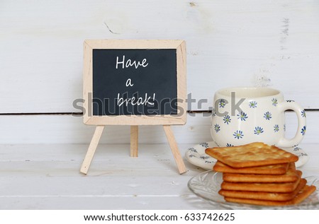 Selective focus, Mini blackboard with text written HAVE A BREAK placed beside coffee cup and crackers, for background and wallpaper
