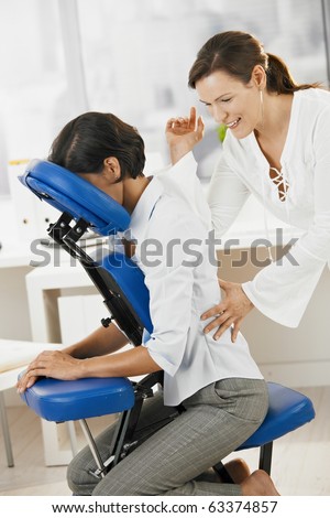 Businesswoman sitting on massage chair, enjoying back massage.?