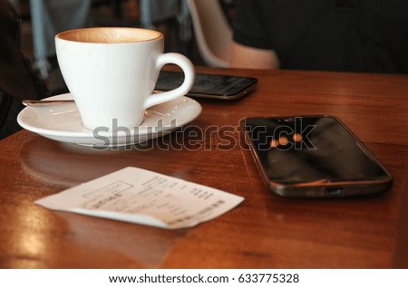 coffee cup and smart phone on wood table , people relax in cafe