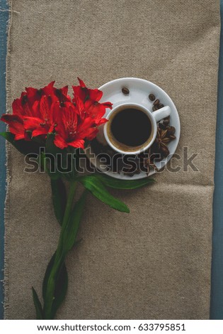 A cup of coffee and a bouquet of flowers on a wooden background
