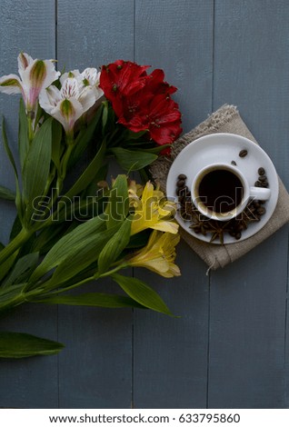 A cup of coffee and a bouquet of flowers on a wooden background