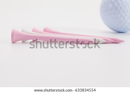 Pink wooden golf tees and golf ball on the white table