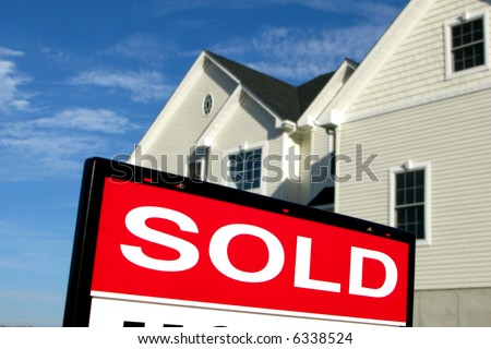 Real estate lawn sign sold rider insert in front of a house for sale by Realtor in a residential neighborhood