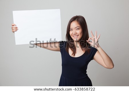 Young Asian woman show OK with  white blank sign on gray background