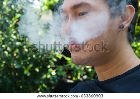 Bearded man with e-cigarette outdoors.Abstract Smoke from Electric cigarette