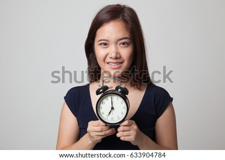 Young Asian woman smile with a clock on gray background