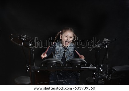 Little caucasian girl drummer playing the elettronic drum kit on black background
