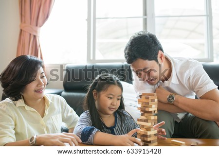 Happy Asian family having fun playing Jenga in the living room