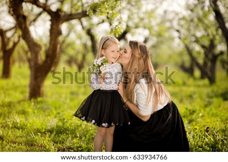 Little daughter gives her mother flowers for the holiday, a walk in the spring garden