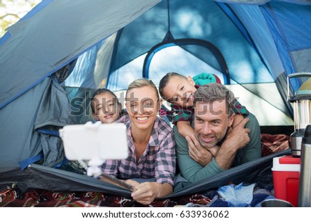 Smiling family taking selfie in the tent at campsite