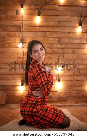 beautiful girl posing for the camera on brown wood background in checkered shirt