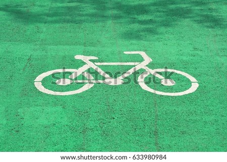 White bicycle sign painted on an green asphalt road.