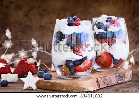 Trifle made with blueberries, strawberries, whipped cream and star shaped pound cake against a rustic background. Perfect for fourth of July. Shallow depth of field with selective focus.