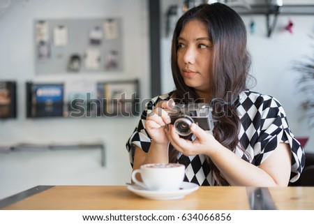 woman using film camera retro hipster style in coffee shop with hot coffee / woman and camera 