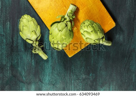Vibrant green artichokes on dark rustic textures with a place for text, overhead photo