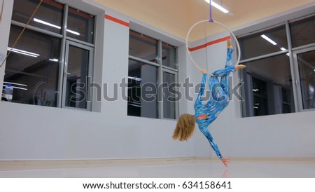 Plastic beautiful girl gymnast on acrobatic circus ring in blue suit. Aerial ring. Acrobatic and sport concept