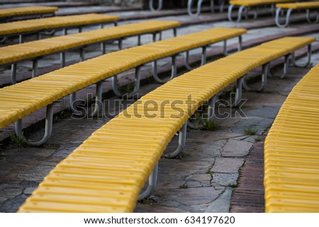 A picture of the empty yellow benches at the decadent stadium. Vibrant colors.