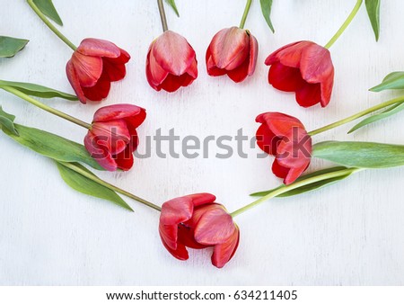 love concept/red tulips heart on white wooden background