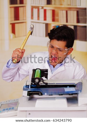 Handsome man screaming while he is fixing a toner during maintenance using a hammer