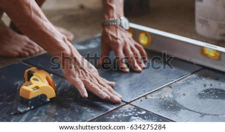 Ceramic Tiles. Tiler placing ceramic wall tile in position over adhesive with lash tile leveling system.selective focus Royalty-Free Stock Photo #634275284