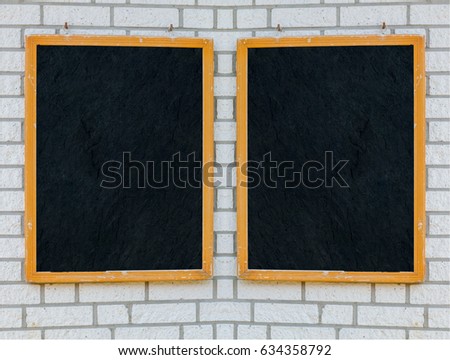 Two empty large slate boards with wooden frame on a stone wall.