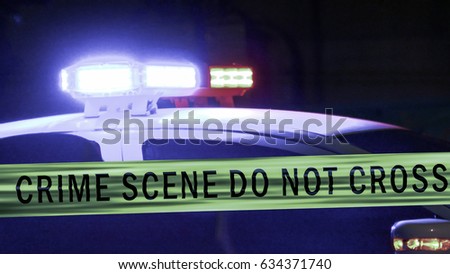 Close-up on siren on police car flashing, with crime scene boundary tape