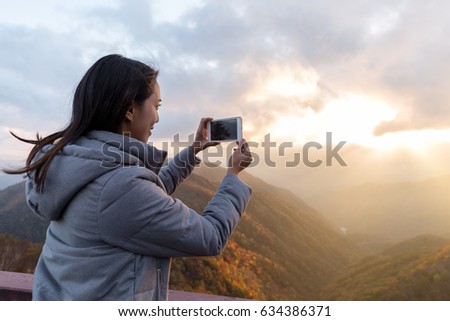 Young Woman taking photo on cellphone at Mount Hangetsuyama during sunset