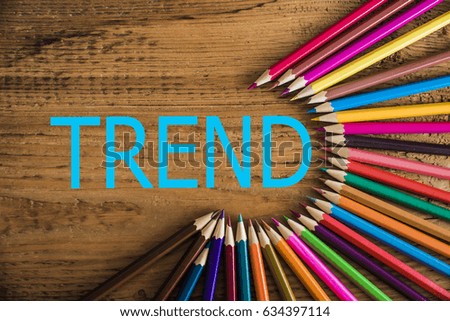 color pencils arranged in a circle on wooden background, top view. Set of multicolored pencils lying on wooden table round order. wooden background. word - TREND inside round