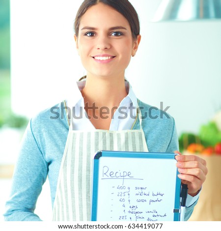 Woman in the kitchen at home, standing near desk with folder