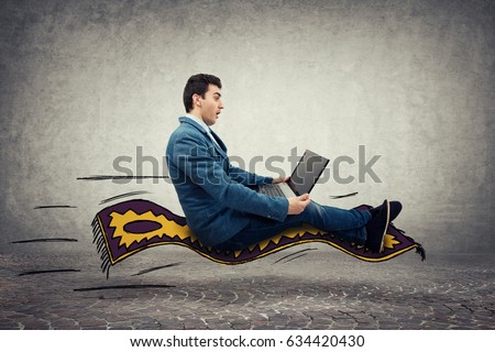 Amazed young businessman looking at a laptop monitor while riding a magic flying carpet.  Global network speed concept.