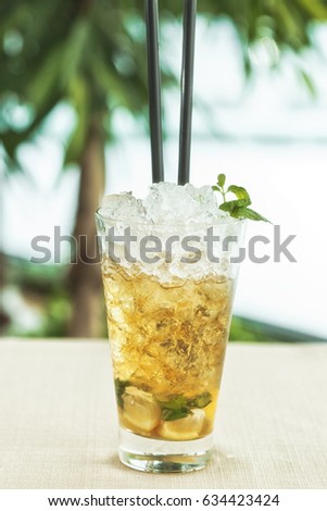 A freshly made summer sweet ice-tea with a fresh mint and lemon served on a crushed ice in a cup with straws