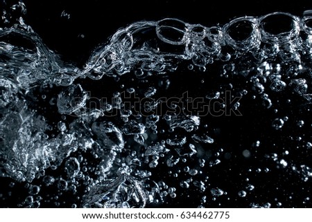 Bubbles, stream and splashes in aquarium on black background