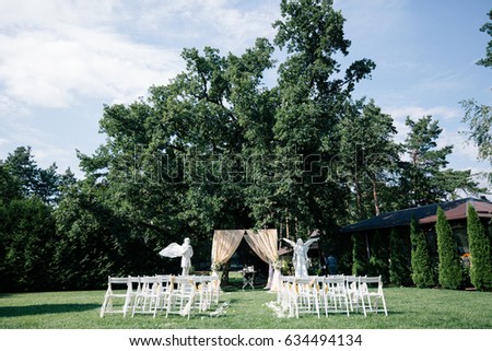 Wedding decorations for the ceremony outside in sunny weather in a beautiful garden. Beautiful wedding archway with chairs on on each side for the guest on the wedding ceremony.