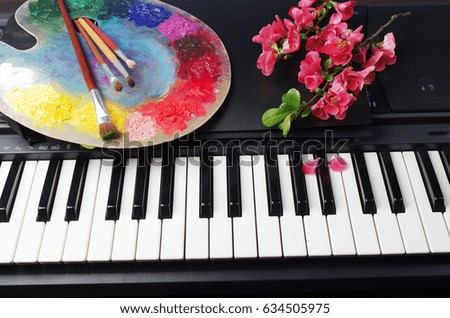 Piano keyboard, art palette and brushes, flowers.