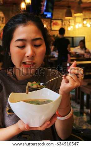 Girl in a somtum(Papaya salad) shop.With on the face shows a delicious spicy.