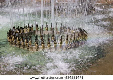 High pressure metal nozzles on fountain spraying jets of water into the air in ornamental display, close up view