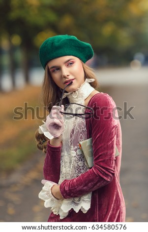 Fashion shot. Student girl back to school university photo. Beautiful woman posing at campus of univercity. Young teen model in hat and glasses with notebook in trendy clothes