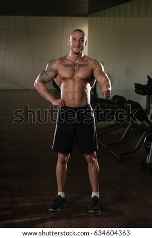 Muscular Man Showing Thumbs Up While Standing Strong In A Gym And Flexing Muscles - Muscular Athletic Bodybuilder Fitness Model Posing After Exercises
