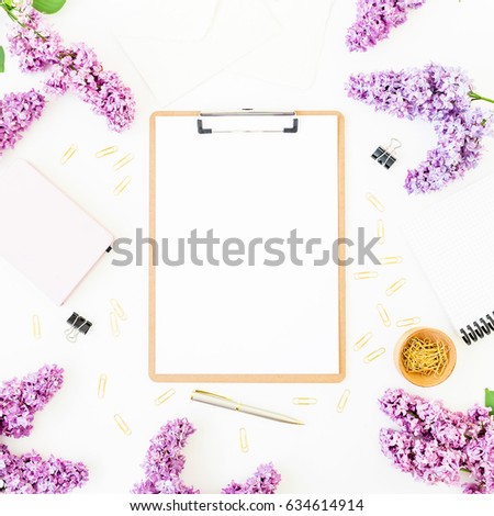 Minimalistic workspace with clipboard, notebook, pen, lilac and accessories on white background. Flat lay, top view. Beauty blog concept.