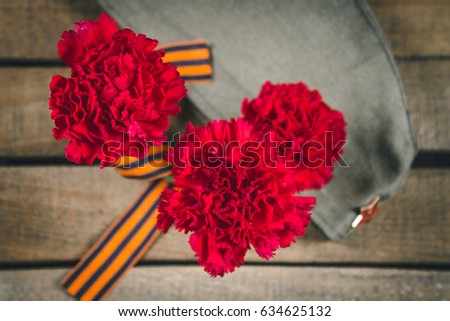 Carnation flowers, George Ribbon and military garrison cap with a red star. May 9 Victory Day.