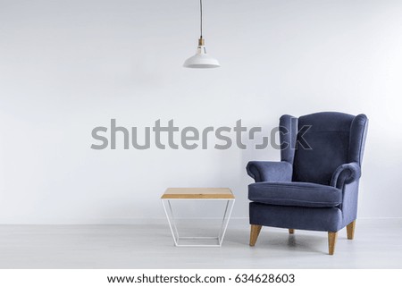 Wooden coffee table and blue armchair in simple room