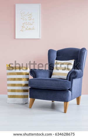 Pink lounge with blue comfortable armchair and golden decoration