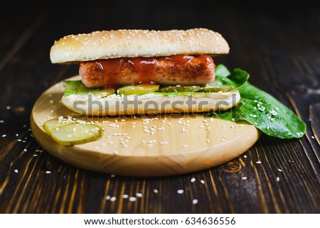 delicious classic American hotdog with sausage, ketchup, lettuce, pickles on a sesame seed bun